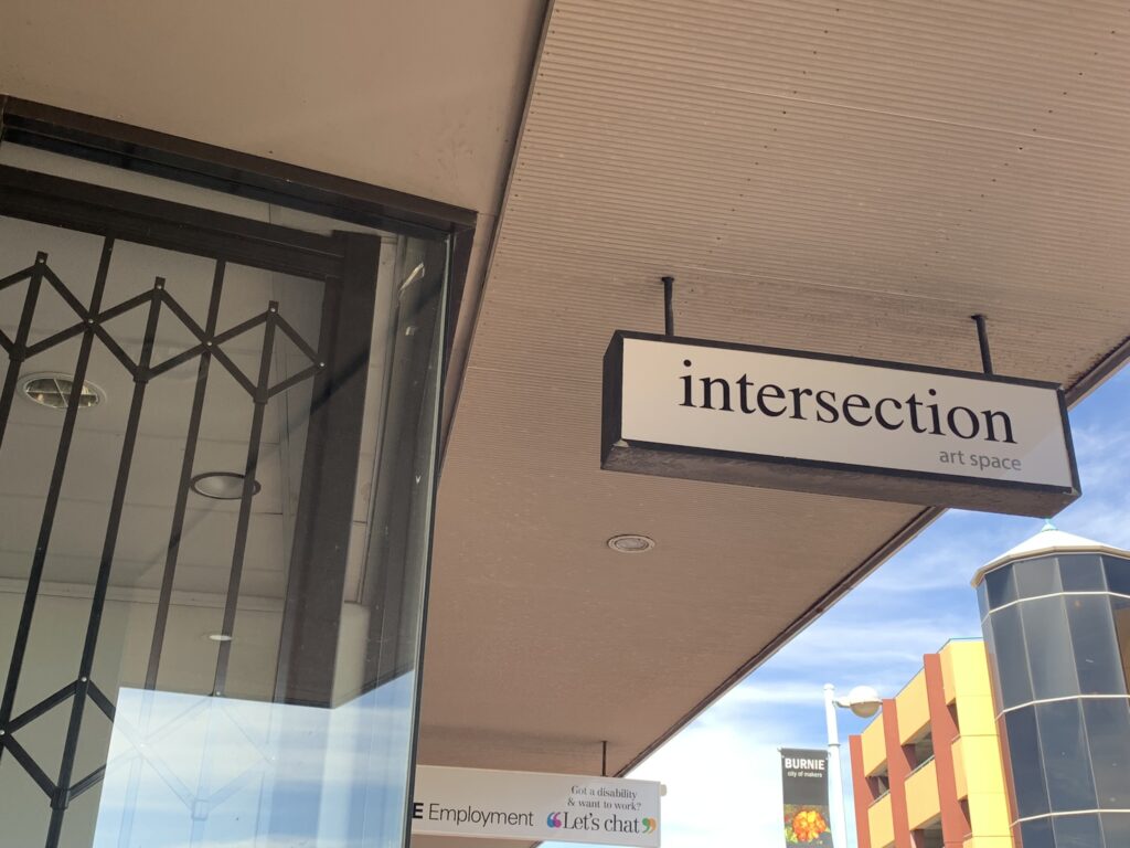 Intersection art space signage, done in a black and white letering shon looking from below looking up.